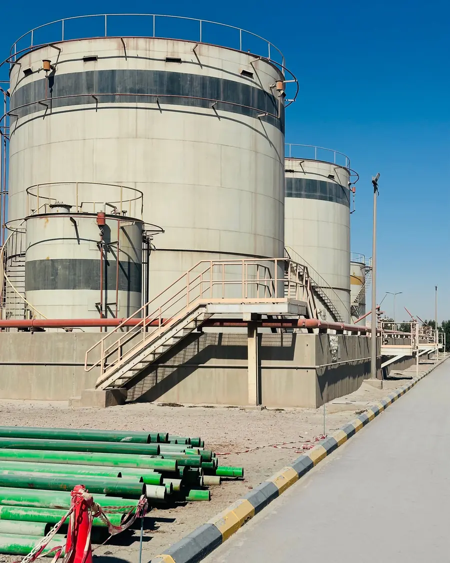 Oil storage tanks with stacked line pipe at a process facility