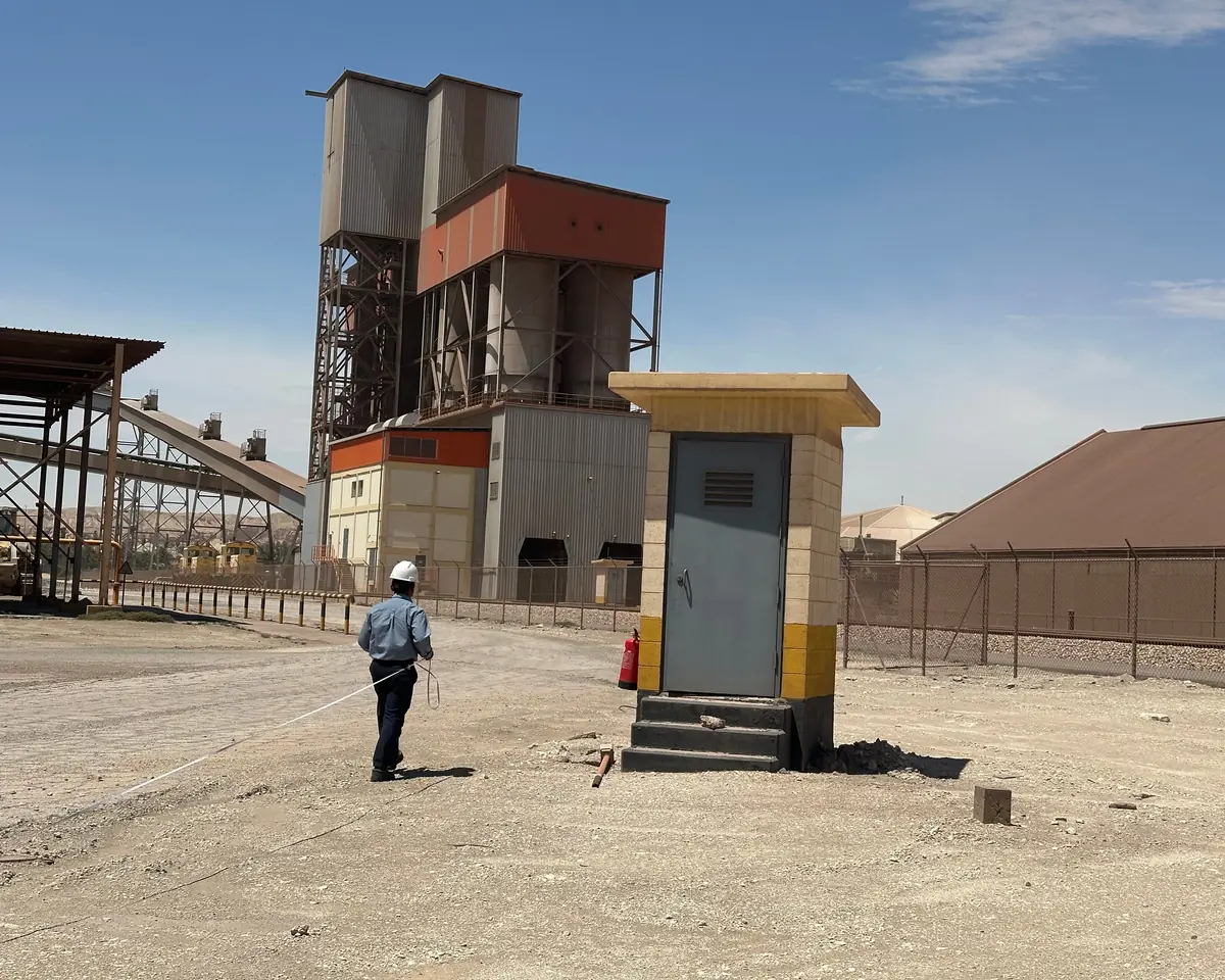 Engineer in a hard hat walking across an industrial plant yard